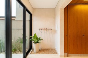 A modern interior with a wooden door, a potted plant, and a wall-mounted rack. - Modern House: 3 Suites | Jacuzzi | 450m from Beach (Florianópolis)