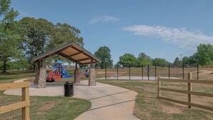 Un parque con un pabellón cubierto, un parque infantil y un área cercada.