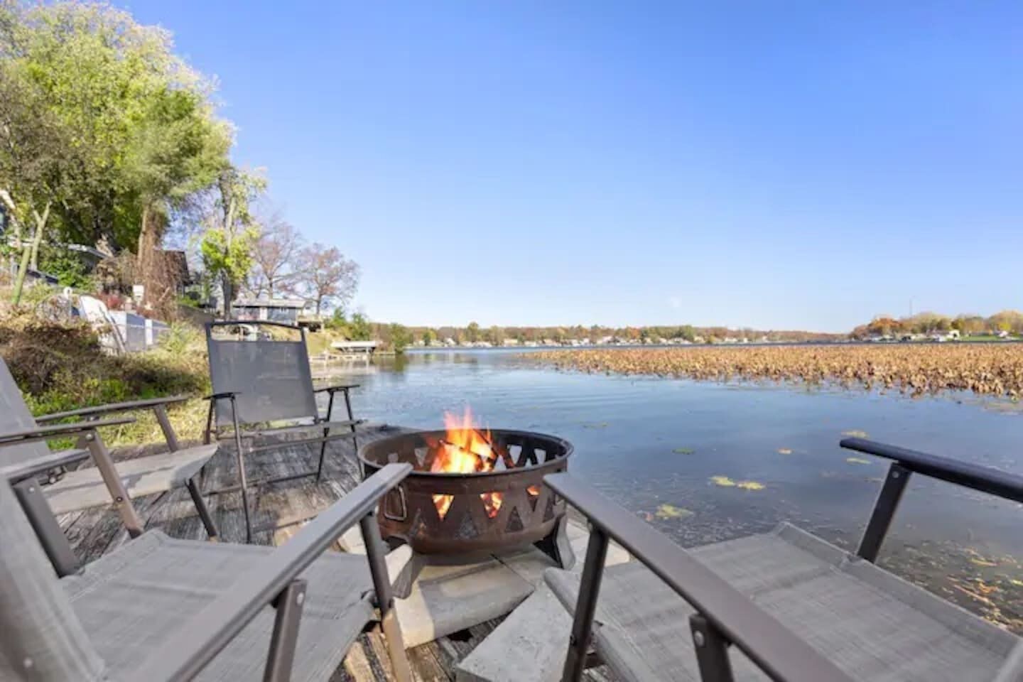 Une terrasse au bord de la rivière, avec un foyer, des sièges et une vue sur l’eau.