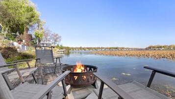 Une terrasse au bord de la rivière, avec un foyer, des sièges et une vue sur l’eau.