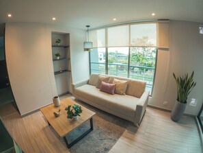 A modern living room with a sofa, coffee table, and shelves. - Santorini Apartamentos amoblados (Pereira)