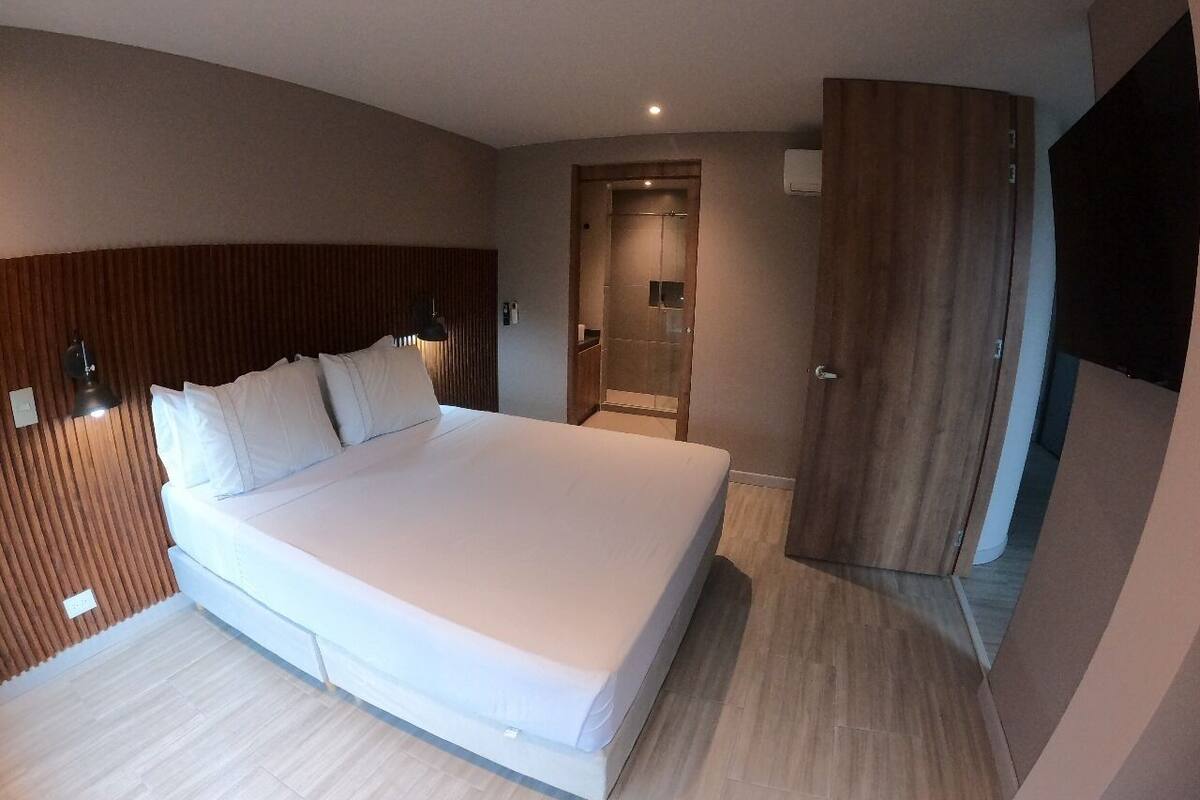 Ein modernes Schlafzimmer mit einem großen Bett, einem Holzkopfende, einem Kleiderschrank und einem begehbaren Kleiderschrank.