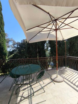 A patio with a table and chairs, an umbrella, and a railing.