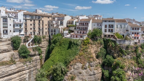 Un pueblo costero con edificios de varios pisos, algunos con balcones, asentado sobre un acantilado rocoso.