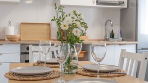 Una mesa de comedor dispuesta con platos, cubiertos y un jarrón de flores.