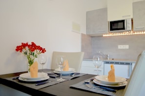 A dining table set with plates, glasses, and a vase of flowers. - Sea View Apartment Mariana (Preko)
