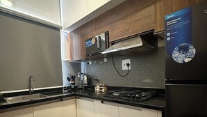 Eine moderne Küche mit weißen Schränken, einem schwarzen Kühlschrank und einer Mikrowelle.