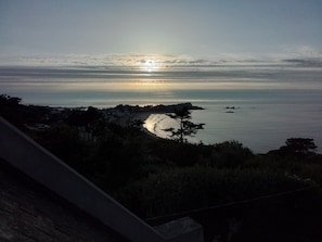 Paisaje costero con atardecer, playa y acantilado.