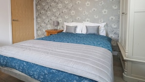 Ein Schlafzimmer mit einem Bett, einem Nachttisch, einer Lampe und einem Kleiderschrank.