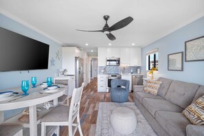 Ein modernes Wohnzimmer mit einer Couch, einem Esstisch und einer Küche im Hintergrund.