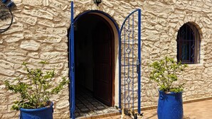Un edificio de piedra con una gran entrada en arco, una verja azul y dos macetas con plantas.