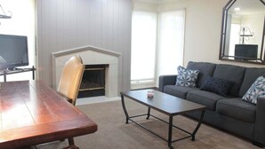 Ein Wohnzimmer mit Kamin, einer Couch, einem Couchtisch und einem Fernseher.