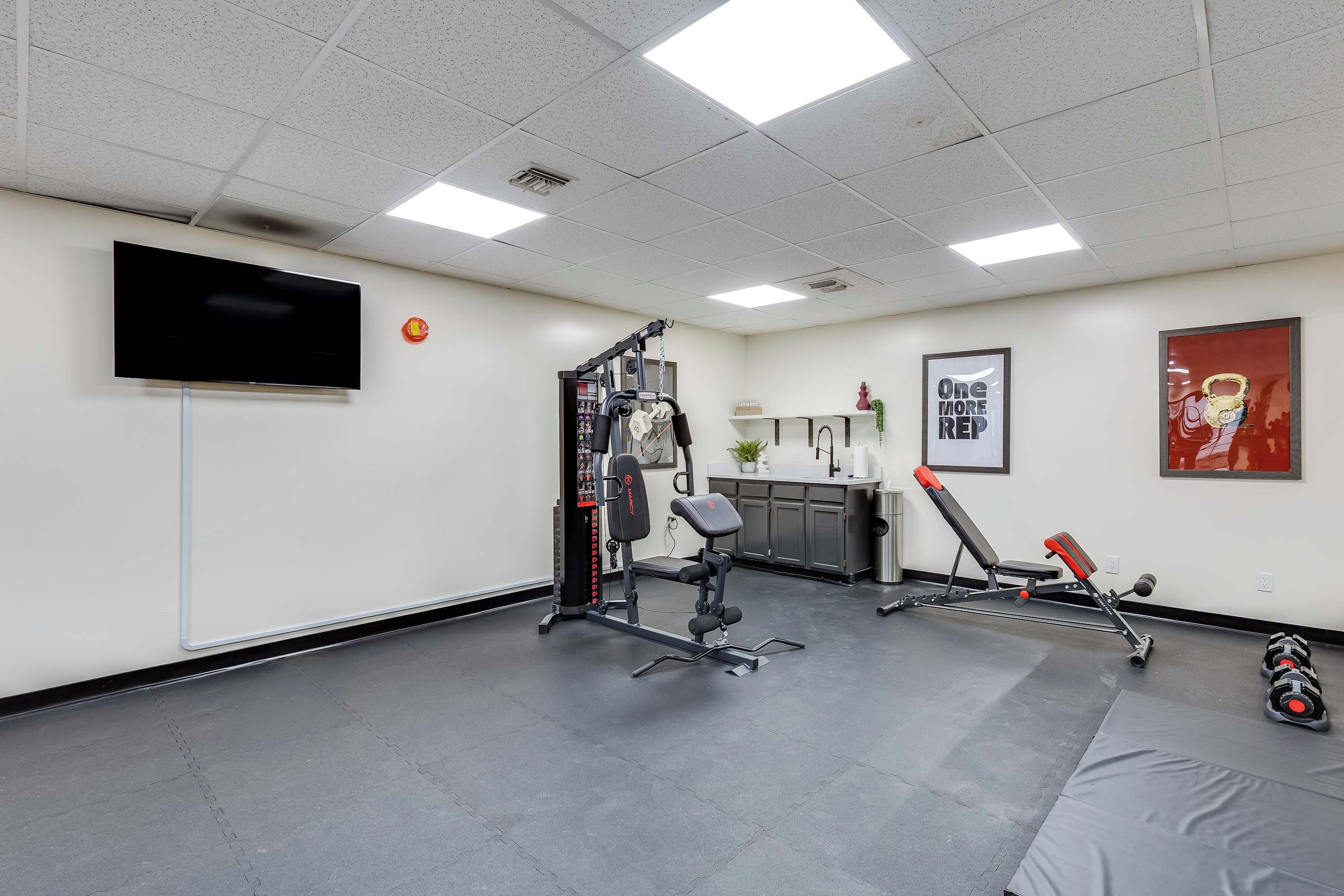 A gym with exercise equipment, a television, and a motivational poster.