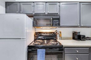 Une cuisine équipée d’un réfrigérateur, d’un four à micro-ondes, d’une cuisinière et de placards.