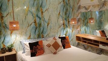 A hotel room with a marble-patterned wall, a bed with white bedding, and two hanging lamps.