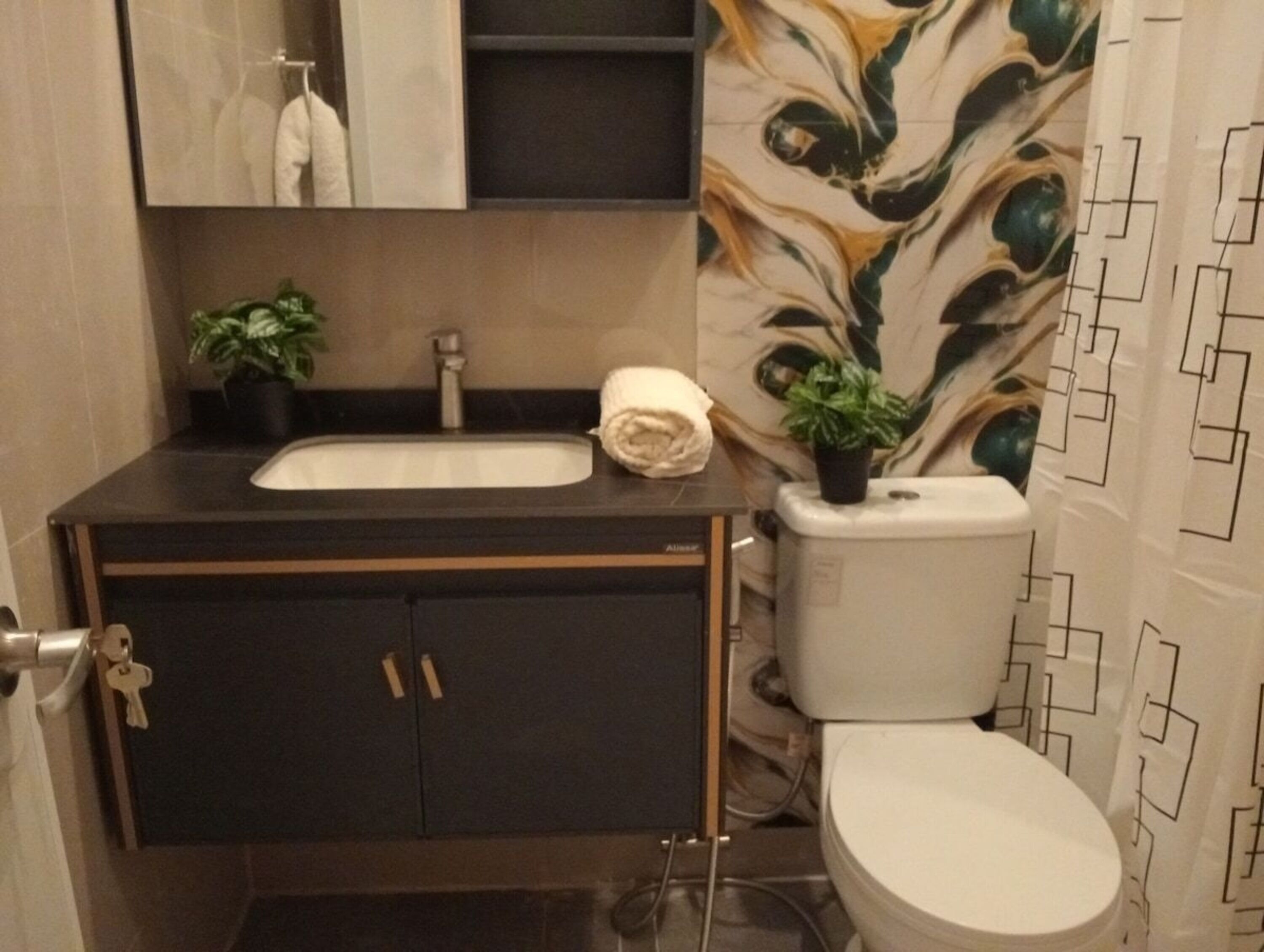 Un baño con lavamanos, inodoro, armario y espejo.