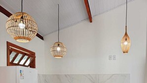 A kitchen with a white refrigerator, black sink, and wooden countertop. There are three hanging pendant lights. - Cozy beachfront house for you to relax with family, friends, and pets! (Caraíva)