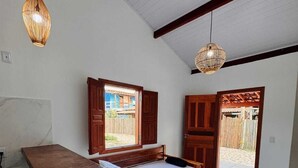 A bedroom with a bed, wooden furniture, a small table, and two hanging lights. - Cozy beachfront house for you to relax with family, friends, and pets! (Caraíva)