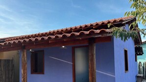 A single-story house with a tiled roof, a blue exterior, and a wooden porch. - Cozy beachfront house for you to relax with family, friends, and pets! (Caraíva)