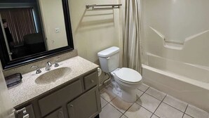 A bathroom with a sink, mirror, toilet, and shower. - Two Bedroom First Floor (Wichita)