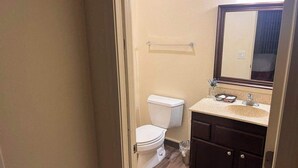 Een badkamer met toilet, wastafel, spiegel en houten vloer.