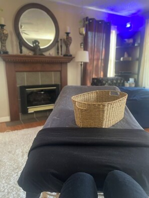 Ein Zimmer mit einem dunkelbraunen Sofa, einem Korbwäscheschrank, einem Kamin und einem Spiegel an der Wand.