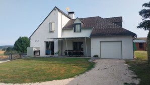 Een huis met twee verdiepingen, een overdekte patio, een garage en een omheinde tuin.