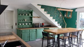 Een keuken met een groene kleurenschema, een houten eettafel en een trap met een bijzonder ontwerp.