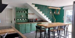 Eine Küche mit Grün-Tönen, einem Holzesstisch und einer Treppe mit ungewöhnlichem Design.