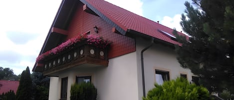 A building with a red-tiled roof, a balcony with flower boxes, and a white facade.