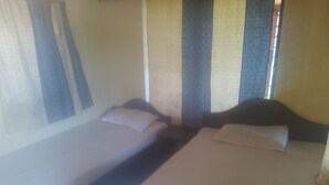 A room with two beds, a window with curtains, and a wall with a patterned design.