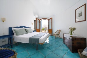 Ein Schlafzimmer mit einem Bett, einem Sessel, einem kleinen Tisch und einer Holzkiste.