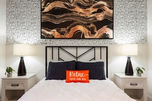 A bedroom with a bed, two nightstands, two lamps, a wall art piece, and a decorative pillow with text. - Luxury TPC | Heated Pool | Barrett-Jackson+Parking (Scottsdale)