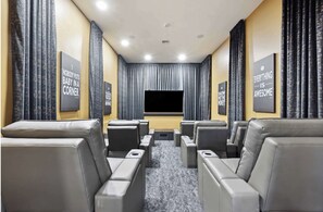 A home theater room with a large screen, multiple seating areas, and motivational posters on the walls.