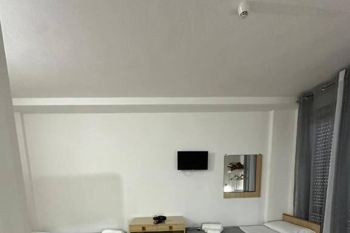 Hotellihuone, jossa on kaksi erillistä sänkyä, yksi suurempi sänky, työpöytä, tuoli, taulutelevisio ja peili.