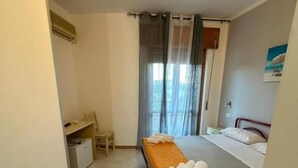 Una habitación de hotel con cama, escritorio, silla y ventana con cortinas.