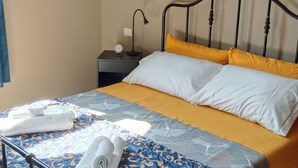 A bed with a patterned bedspread, two pillows, and a rolled towel on the side. - Double room with private bathroom (La Spezia)