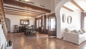 A spacious living area with a dining table, chairs, a sofa, and a chandelier. - Villa Wioleta - Costa CarpeDiem (Benissa, Alicante)