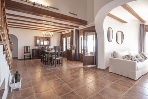 A spacious living area with a dining table, chairs, a sofa, and a chandelier. - Villa Wioleta - Costa CarpeDiem (Benissa, Alicante)