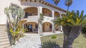 A multi-story building with a courtyard, featuring a staircase, palm trees, and a tiled pathway. - Villa Wioleta - Costa CarpeDiem (Benissa, Alicante)
