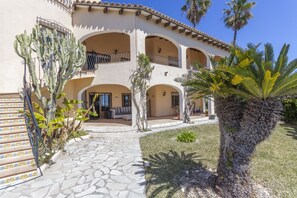 A multi-story building with a courtyard, featuring a staircase, palm trees, and a tiled pathway. - Villa Wioleta - Costa CarpeDiem (Benissa, Alicante)