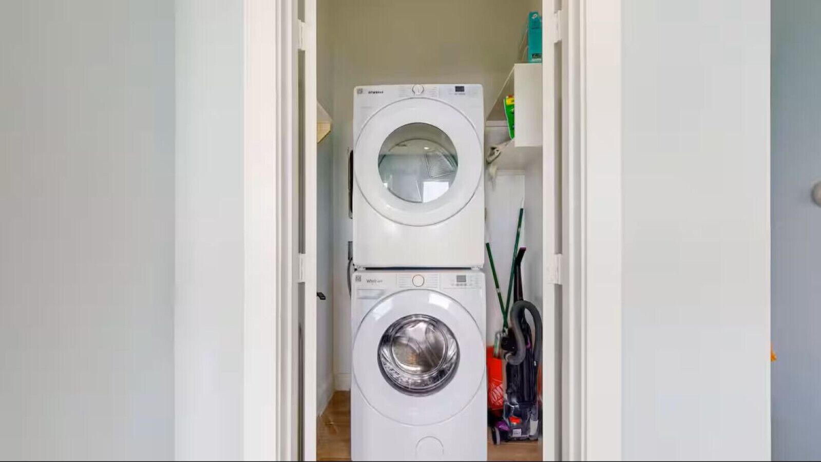 A laundry room with two stacked washing machines and a shelf with cleaning supplies.