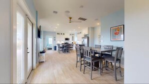 Une cuisine moderne avec des meubles blancs, un coin repas avec des chaises en bois et une grande fenêtre.