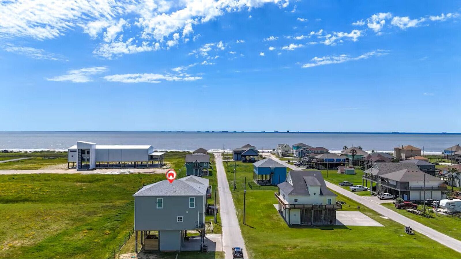 A coastal residential area with houses, a large white building, and a view of the ocean.