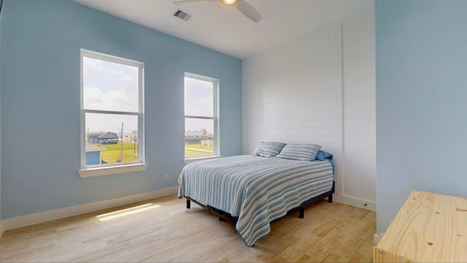 A bedroom with a bed, two windows, and a ceiling fan.