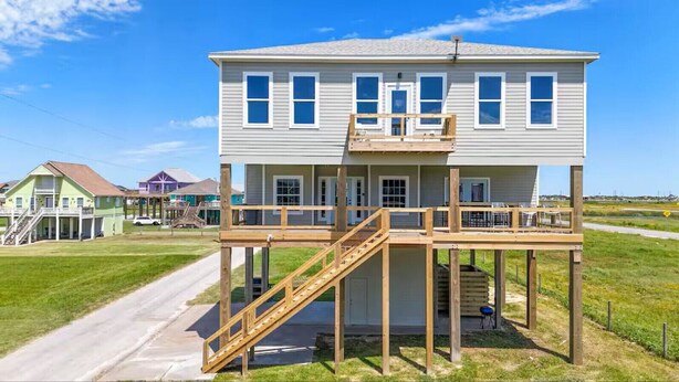 Une maison à deux étages dotée d’une terrasse en bois et d’un escalier.