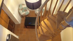 En spiraltrappe, et lille bord med en blå genstand, og en vægmonteret aircondition.