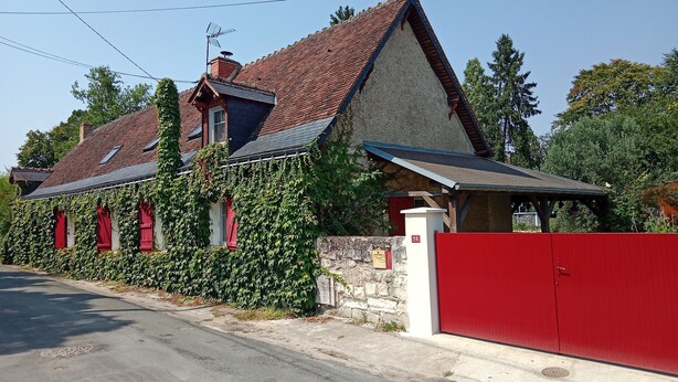 Et hus med en stensokkel, rødt tag og rød garageport.