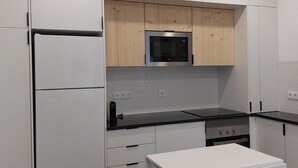 Eine moderne Küche mit weißen Schränken, einem Edelstahl-Kühlschrank, einer Mikrowelle und einem Einbauofen.