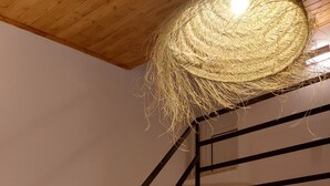 Eine Treppe mit hölzernem Geländer und Steinstufen, die zu einem Raum mit einer Deckenleuchte führt.